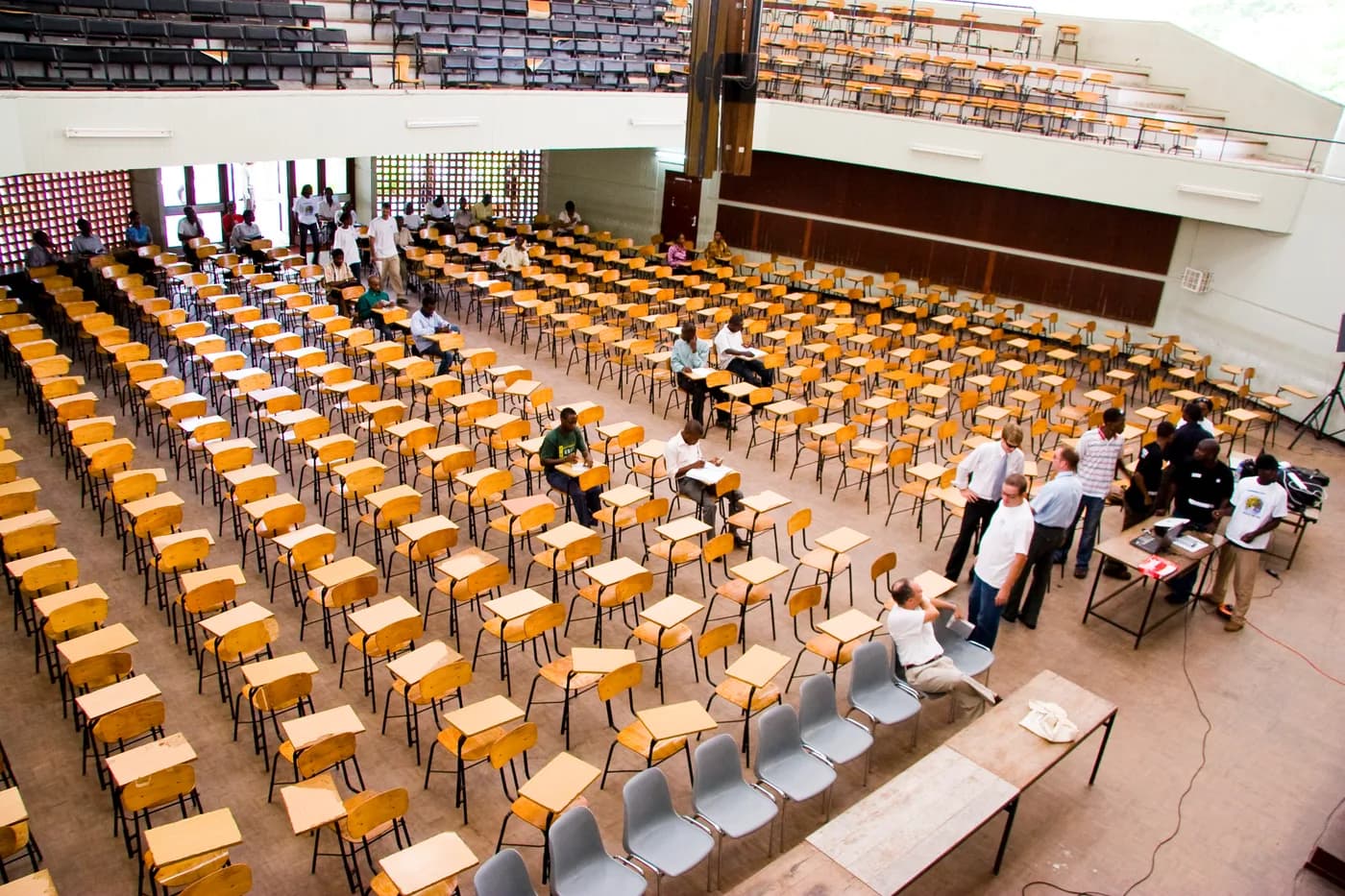 A wide view of Nkrumah Hall, with rows of wooden desks and people gathering inside.